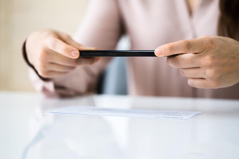 Woman taking a photo of her check with her cell phone.