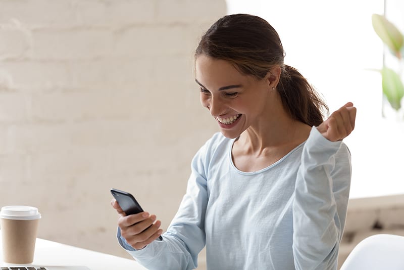 Happy woman using her phone to cash a check.