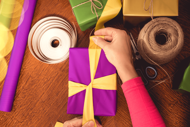 kid decorating gift box with ribbon