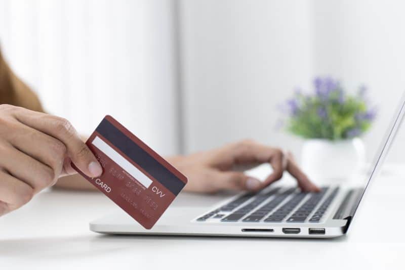 unrecognizable man using a credit card and a laptop to shop online at home
