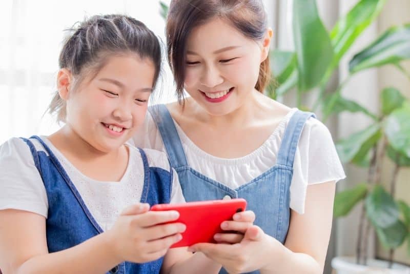 Asian mom with child on her phone.