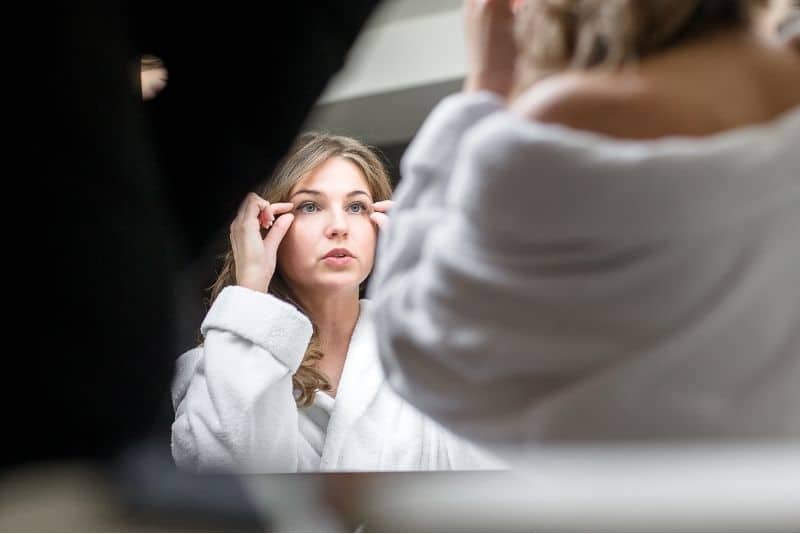 bride looking in the mirror fixing her makeup