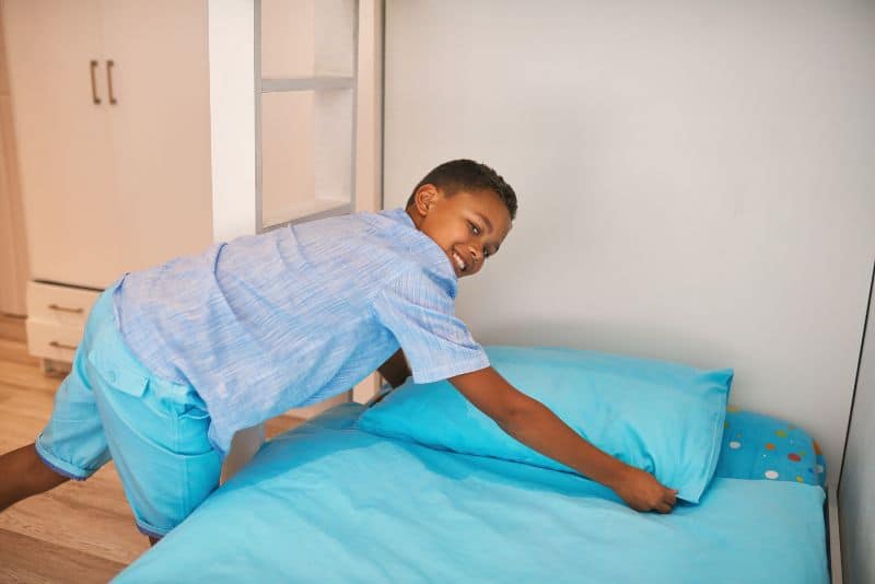 Kid making the bed.