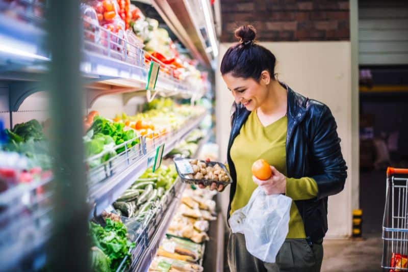 Woman grocery shopping for clean foods.
