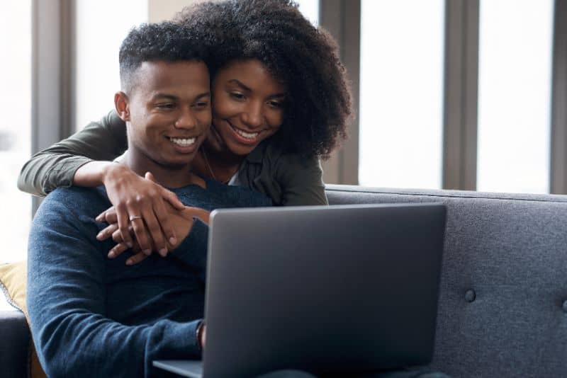 Woman with husband smiling over computer.