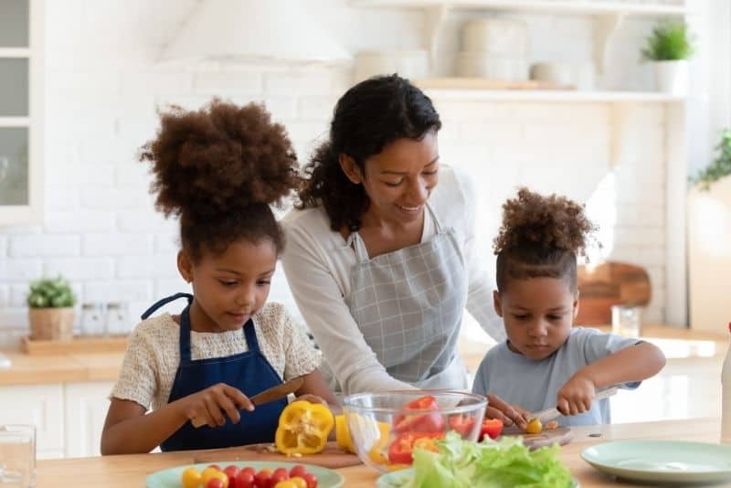 Mom cooking at home with her kids to save money.