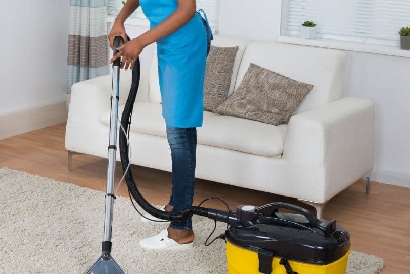 woman using rented carpet cleaner on rug