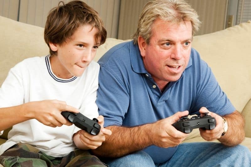 Father and son playing videos games because they are game reviewers as a summer job for teachers.