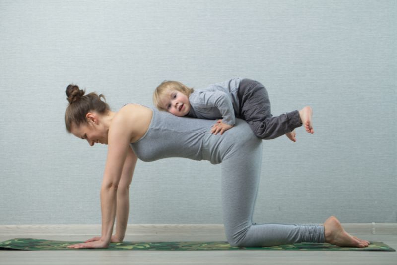 Mom doing yoga with kids.